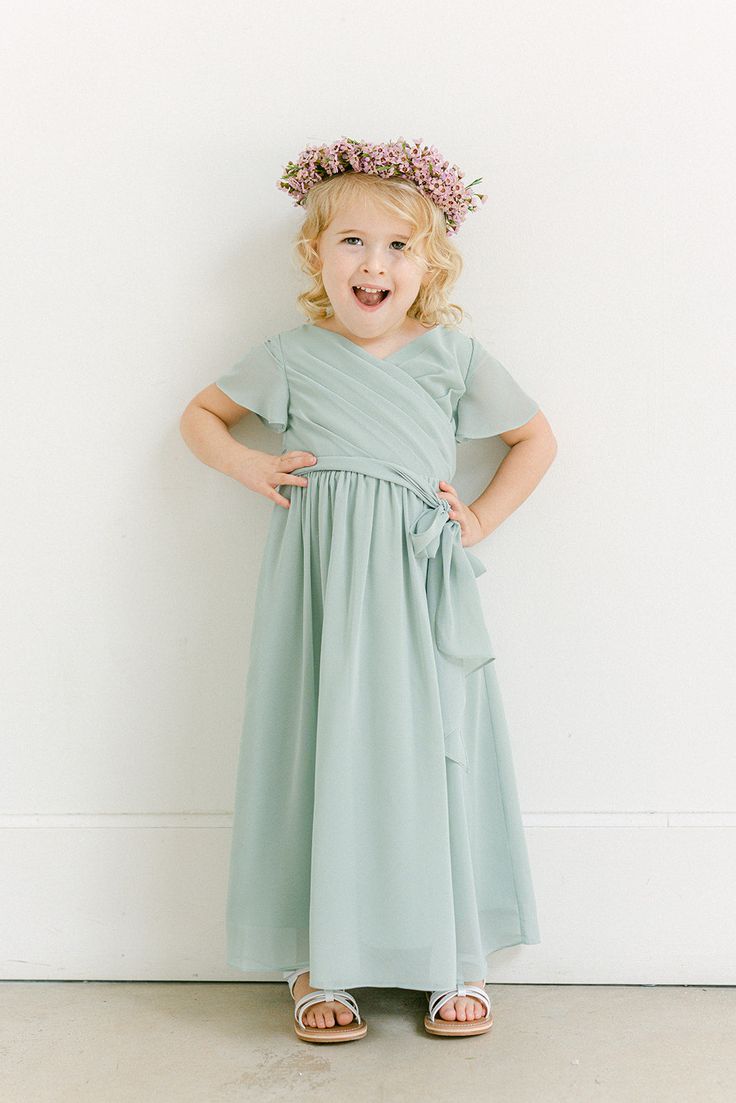 Our Kids Harper Chiffon dress is a nod to our adult faux wrap dress, letting your little one match your wedding party! Kids Harper features delicate bodice pleats, and translucent angelic sleeves, and is finished with an asymmetrical bow for that perfect amount of girly flare! Model Demi; Size: 3T / Length: Regular, Age: 3, Height: 3'0 Model Naveah; Size: 3T / Length: Regular, Age: 2, Height: 3'3 (measurements from 2021) FEATURES: Flowy A-line silhouette Surplice neckline Short sleeves Side zipp Elegant Blue Dress For Confirmation, Chiffon Dresses With Ruffles For Dress-up, Elegant Chiffon Dress For Dress-up Occasions, Chiffon Bridesmaid Dresses With Flutter Sleeve, Bridesmaid Dress With Ruffles And Surplice Neckline, Chiffon Wedding Dress With Surplice Neckline, Girls Pageant Dresses Kids, Green Flower Girl Dresses, Wedding Parties Colors