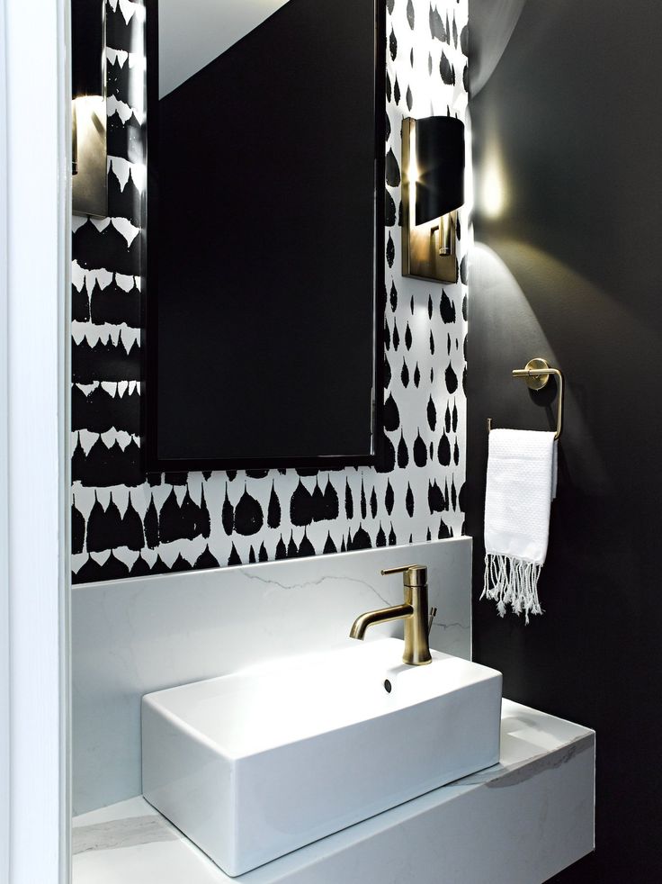 a white sink sitting under a bathroom mirror next to a black and white wallpaper