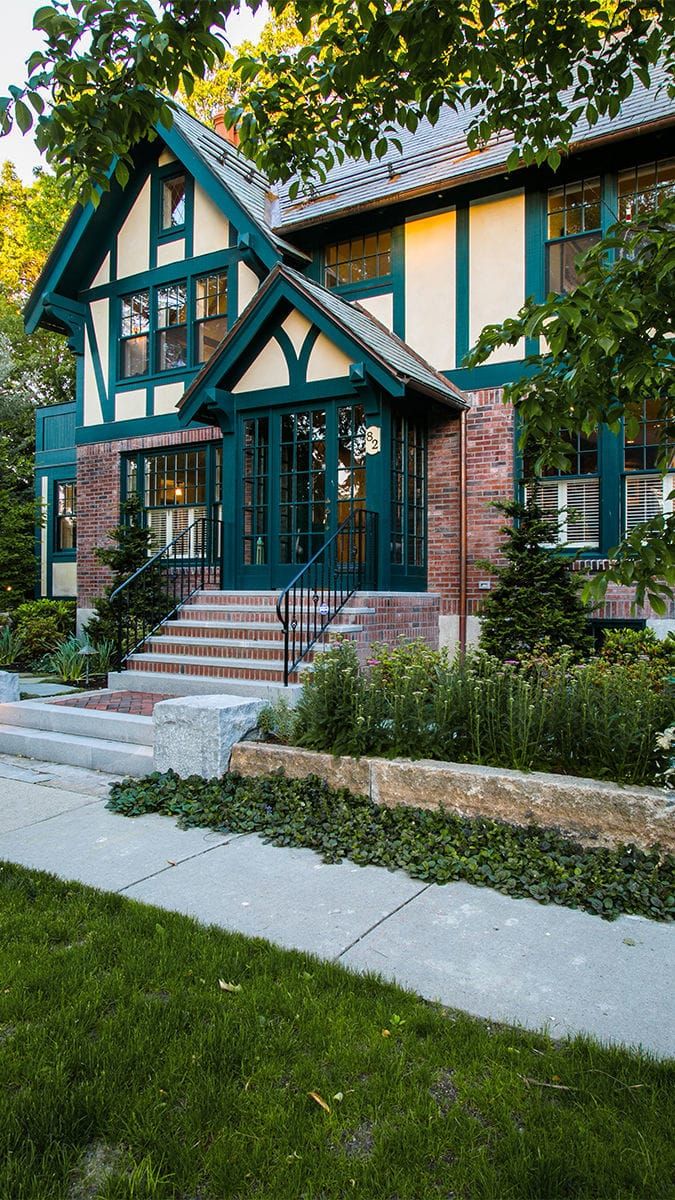 a green and white house with steps leading up to the front door on a sunny day