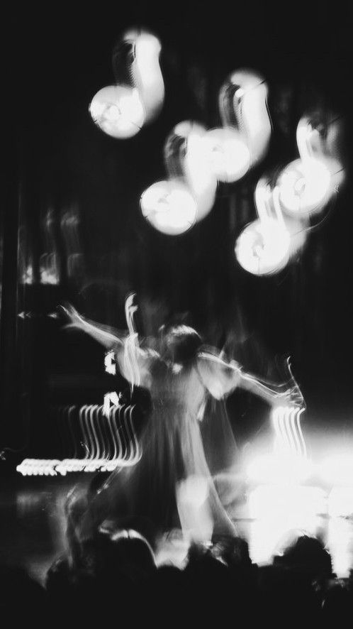 black and white photograph of two people dancing with lights in the air behind them at night