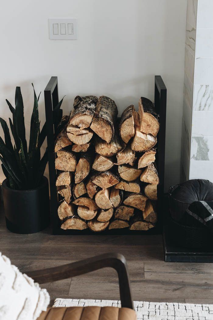 a stack of logs sitting on top of a wooden floor next to a potted plant