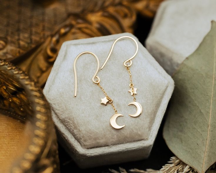 A fashionable piece to add to your jewelry box! You'll have stars in your eyes for these 14K yellow gold mini crescent moon and star drop dangle earrings. Whether worn for a special occasion or as a statement piece for everyday elegance, these chain earrings strike a perfect balance between classic sophistication and modern design, making them a versatile and luxurious addition to any jewelry collection. Product Details Style: 0.85mm 14K Yellow Gold Crescent Moon & Star Dangle Earrings Back Type Stars In Your Eyes, Star Dangle Earrings, Crescent Moon And Star, Staghead Designs, Everyday Elegance, Average Weight, Moon And Star, Moon Star, Threader Earrings