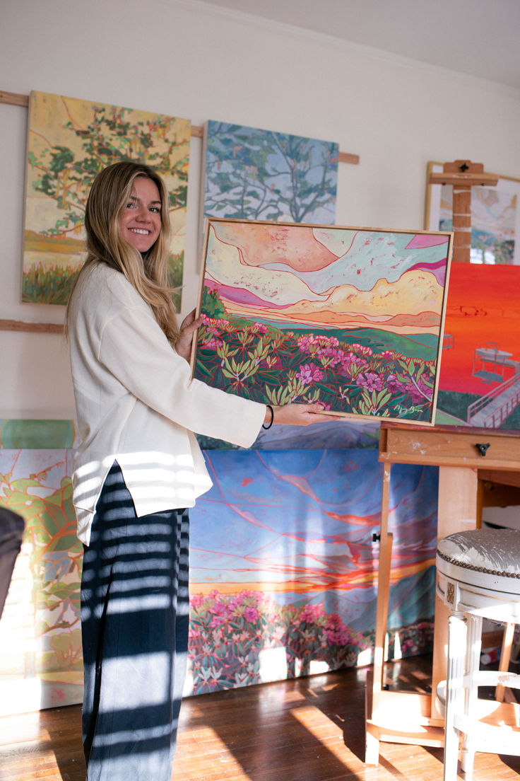 a woman standing in front of some paintings