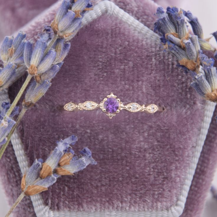 a close up of a ring on a purple velvet surface with lavender flowers in the background