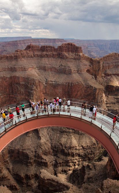 people are walking across a bridge over the canyon