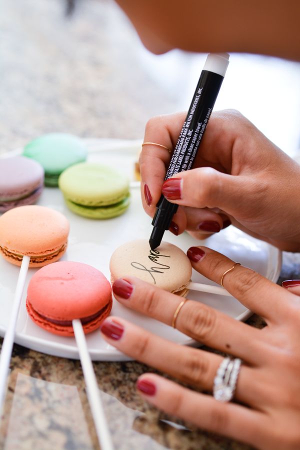 a woman is painting macaroons on a plate with some candy sticks and markers