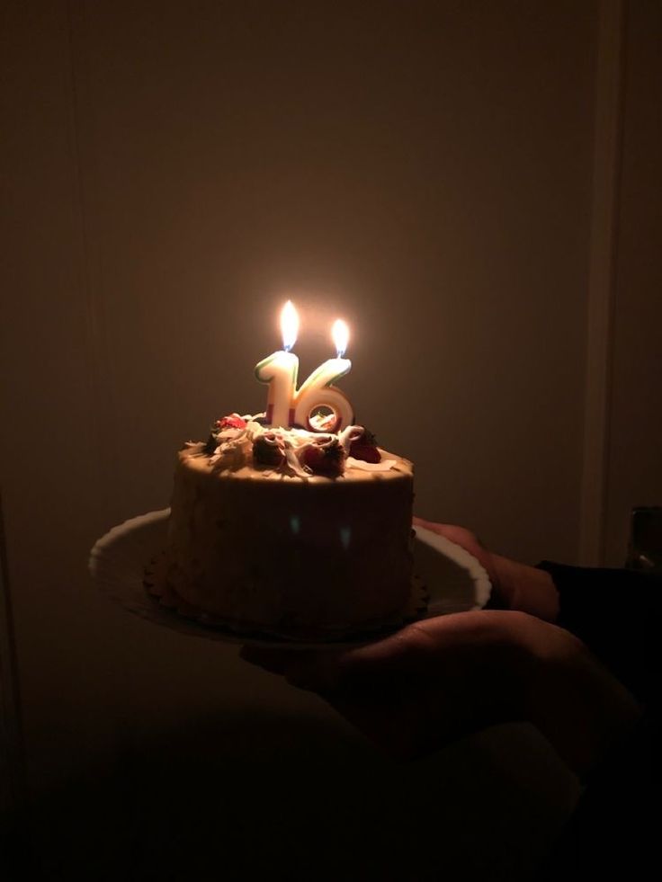 a person holding a cake with two candles on it