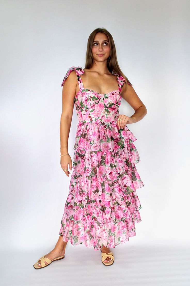 The Olivia Dress is perfect for making a statement with its pink floral print and tiered organza design. The tie straps add a touch of charm while the smocked back ensures a comfortable fit. Elevate your style game with this playful and unique midi dress. Sizing: runs true to size Tiered Party Dress With Tie Straps, Pink Tiered Dress With Adjustable Straps, Pink Tiered Dress For Garden Party, Pink Tiered Skirt Midi Dress For Garden Party, Pink Tiered Ruffle Dress For Garden Party, Pink Midi Dress With Spaghetti Straps And Ruffle Hem, Spring Pink Tiered Dress For Garden Party, Pink Tiered Dress For Spring Garden Party, Fitted Pink Tiered Dress For Garden Party