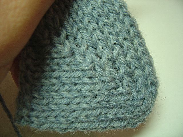 a hand holding a gray knitted object