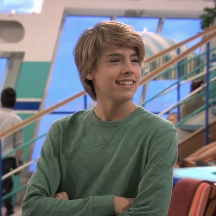 a boy is smiling while standing in front of some stairs with his arms crossed and looking at the camera