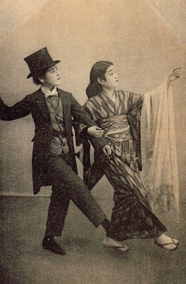 an old photo of two people dressed in fancy clothing, one holding a curtain and the other wearing a top hat