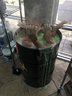 two people are washing their hands in a large tub filled with green liquid while another person looks out the window