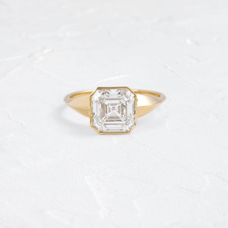 an engagement ring with a square cut diamond in the center, on a white surface