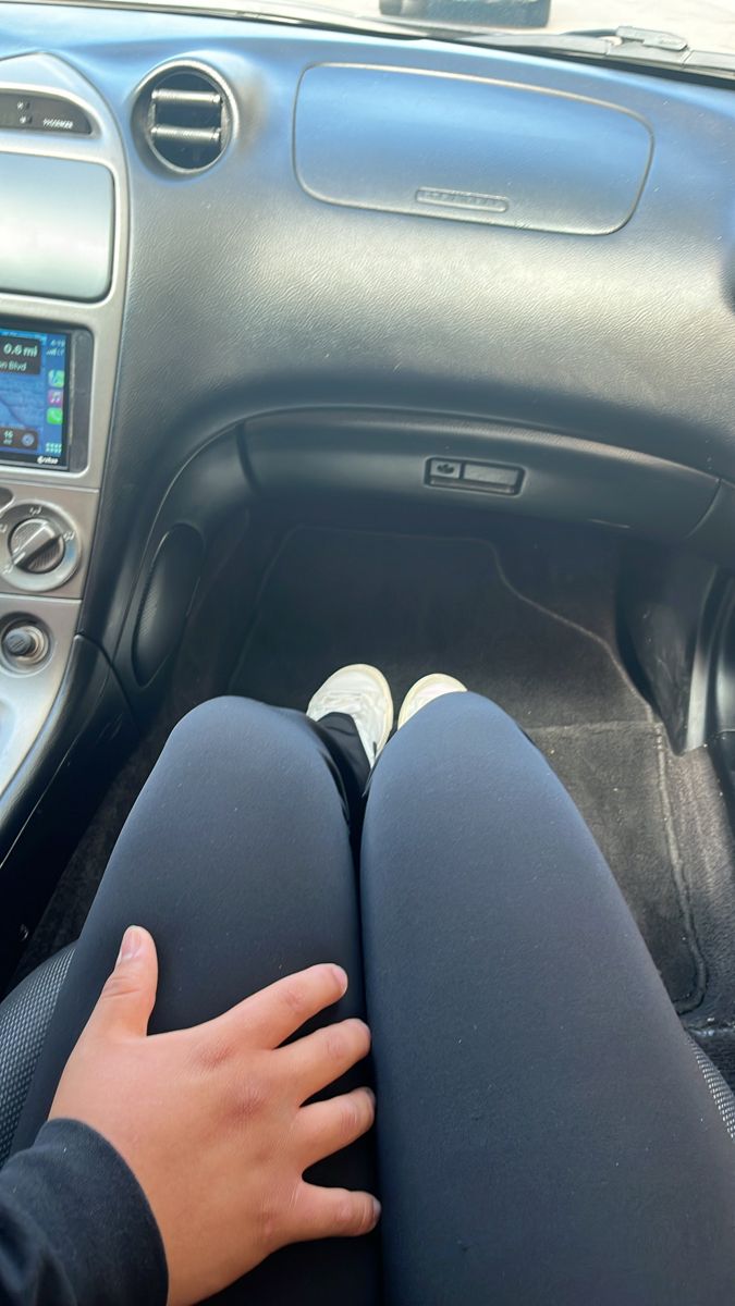 a person sitting in the driver's seat of a car with their hand on the steering wheel