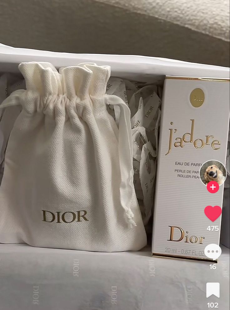 a white bag sitting on top of a bed next to a box with the word dior