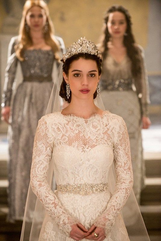 a woman wearing a wedding dress and tiara with other women in dresses behind her