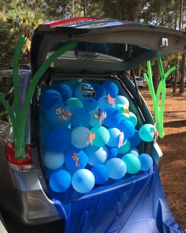 the trunk of a car is filled with balloons and streamers for an ocean themed party