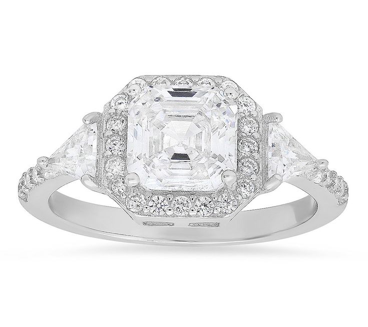 a white diamond ring with three stones on the band and an oval center surrounded by smaller diamonds