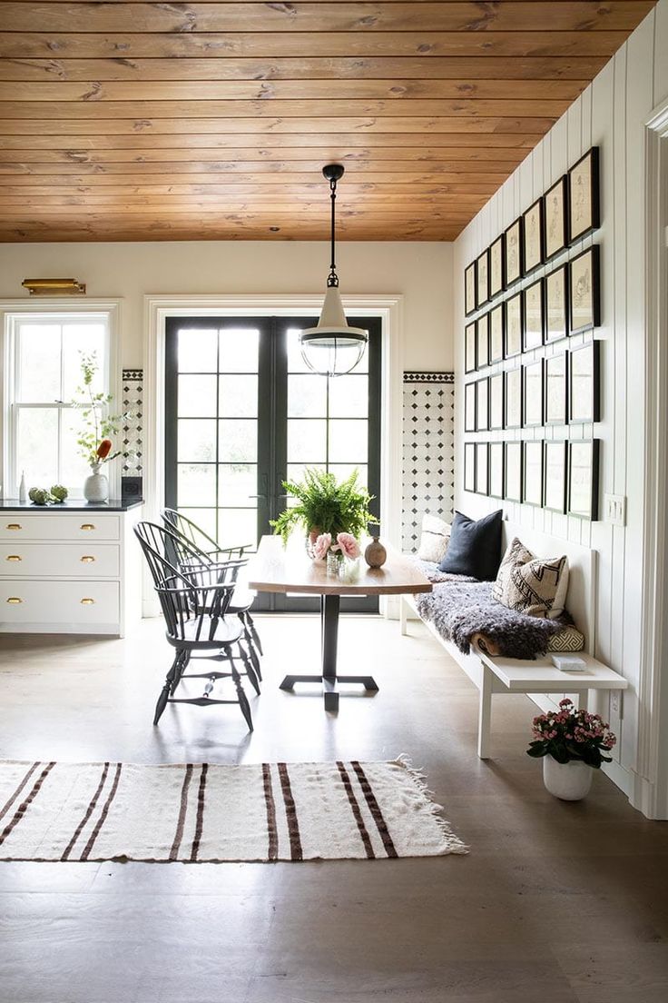 a dining room table and chairs in front of a window with potted plants on it