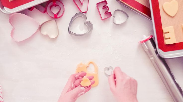 a woman is making valentine's day cookies with cookie cutters and heart shapes