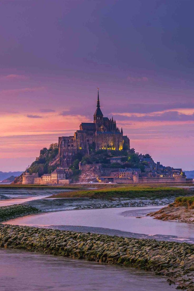 an island with a castle in the middle of it and water at low tide level