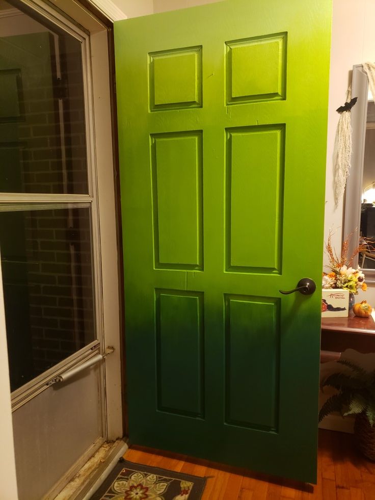 a green door is in the corner of a room with a rug on the floor