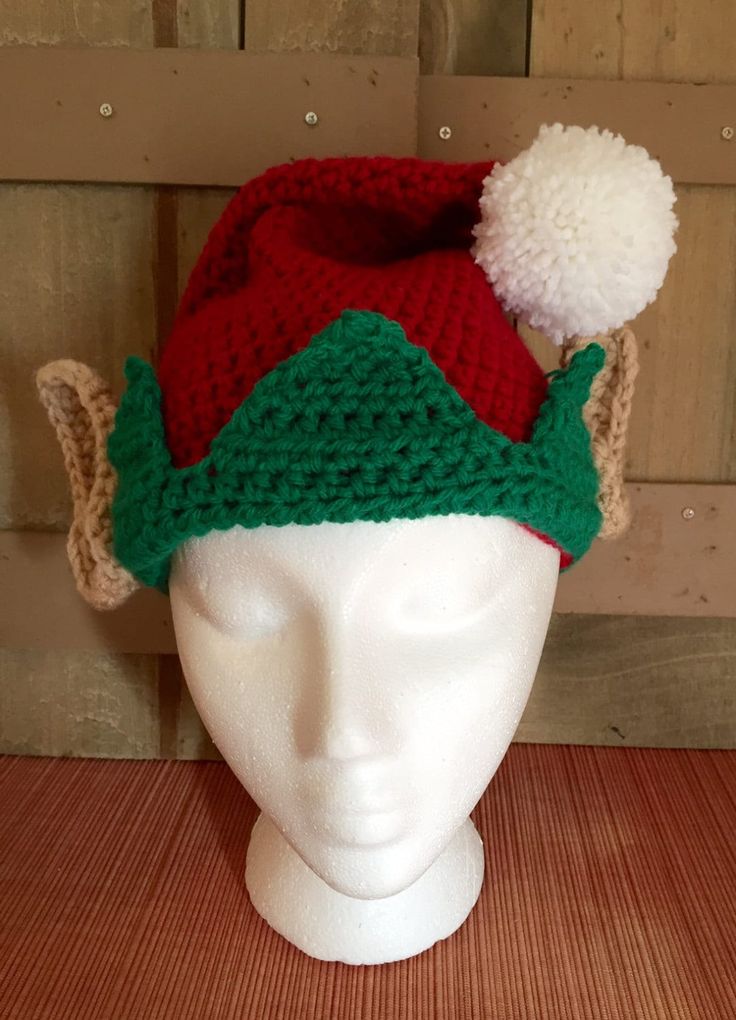 a crocheted hat with two pom poms on top of a white mannequin head