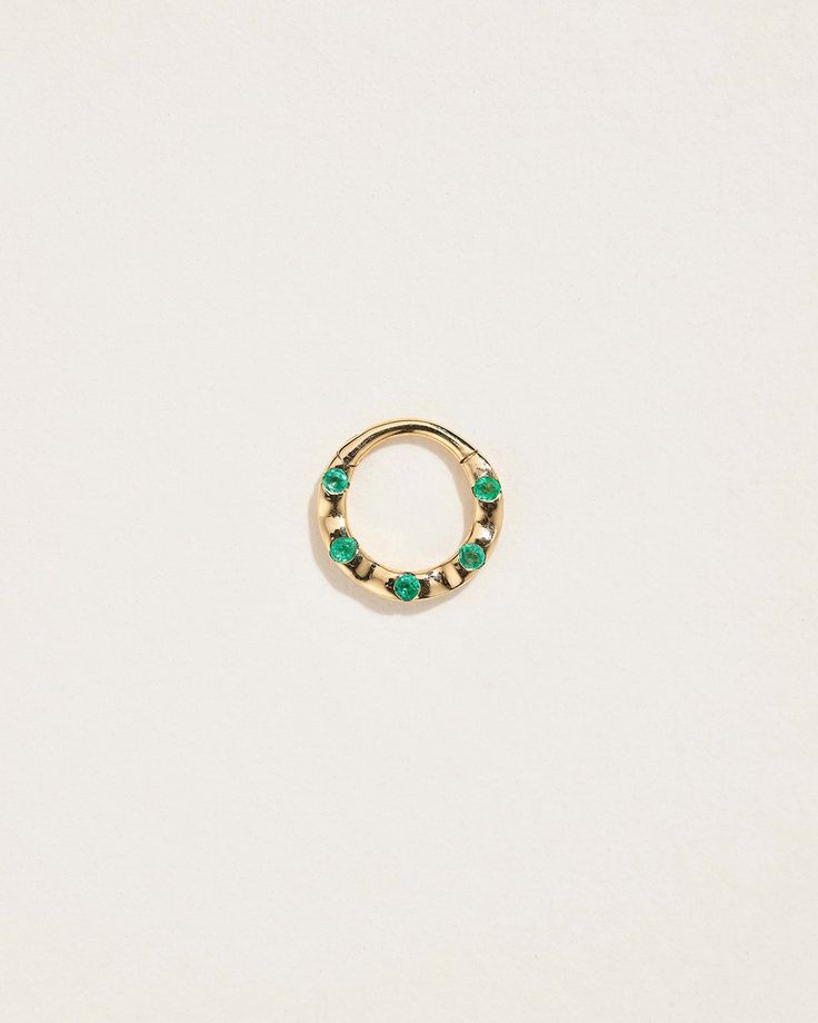 a small gold ring with green stones on the inside, and two smaller beads in the middle