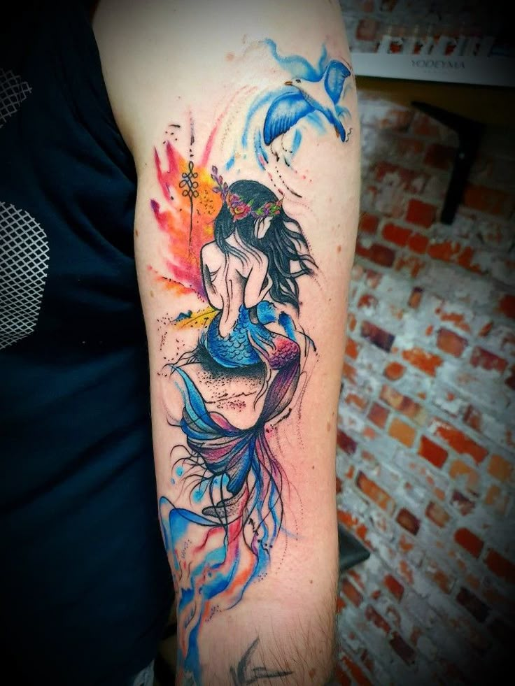 a woman's arm with watercolor tattoos on it