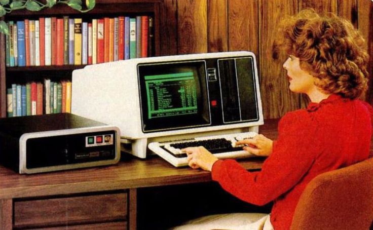 a woman sitting in front of a computer with a keyboard and monitor on top of it