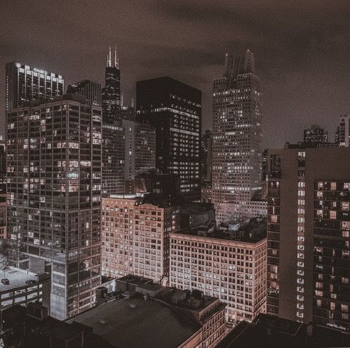 the city skyline is lit up at night, with tall buildings in the foreground