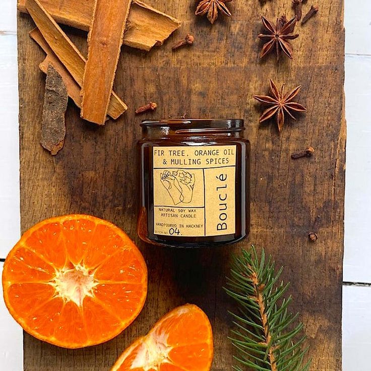 an orange cut in half next to some cinnamons and star anise on a cutting board