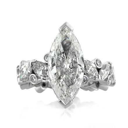 an oval cut diamond engagement ring with three side stones on the band and two claw prongs