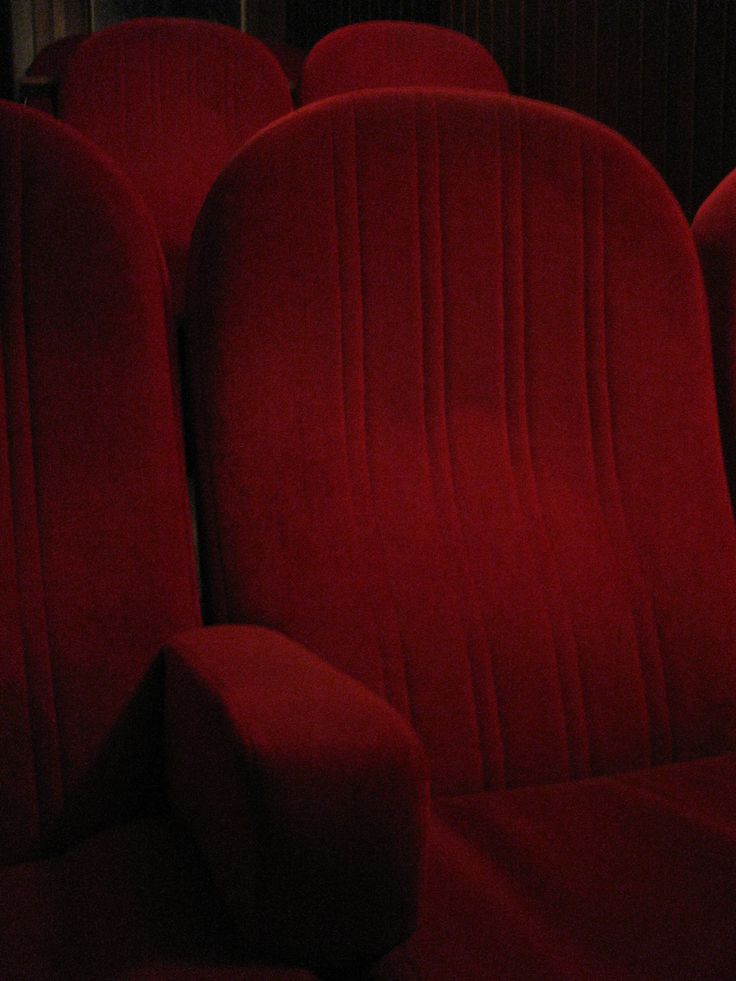 rows of red seats in an auditorium or movie theater, with no people around them