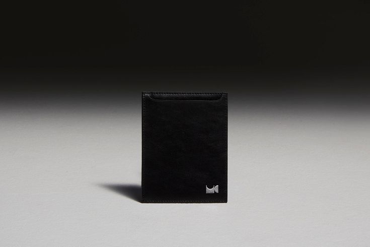 Black leather passport holder sitting in front of black backdrop Functional Rectangular Business Card Holder, Modern Black Card Holder For Formal Use, Modern Black Card Holder For Formal Occasions, Modern Black Formal Card Holder, Black Travel Accessories With Card Slots, Modern Travel Accessories With Rfid Blocking, Modern Rfid Blocking Travel Accessories, Black Minimalist Wallet With Rfid Blocking, Modern Black Card Holder For Travel