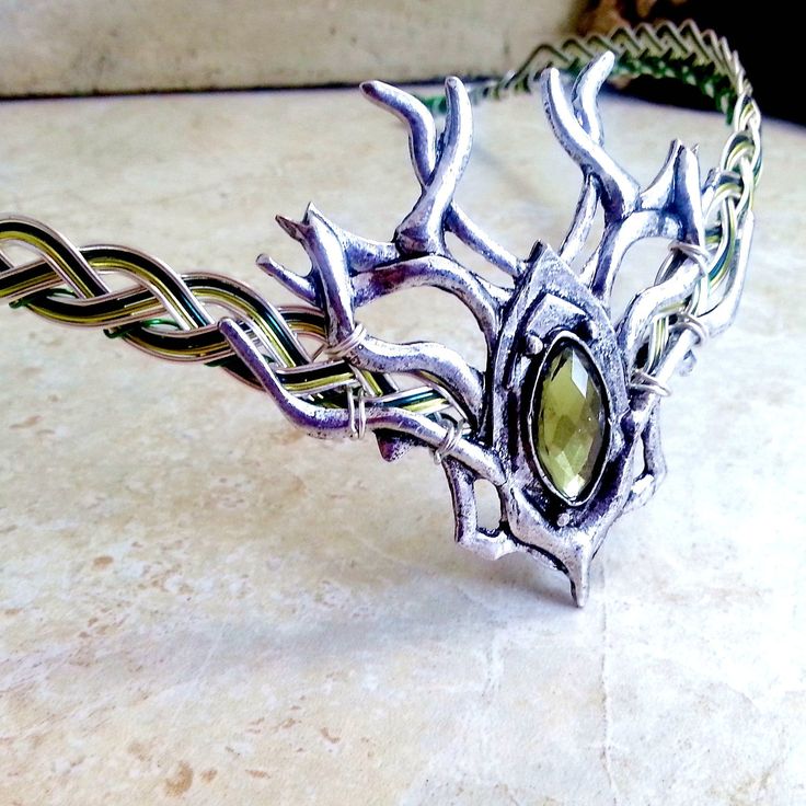 "A woodland stag branch design with a mossy green gem centerpiece is the focal point of this unisex Celtic elven circlet, inspired by the forests of Ireland and Scotland. The Celtic weave base is silver with green accent wires woven in. Three choices of green are available... light green, shown, medium (grass) green, and dark green. Green wire colors will be adjusted accordingly. The circlet can be worn by either men or women and depending on the activity level, can be worn as is, or held in pla Circlet Crown, Elven Circlet, Elven Wedding, Crown Headdress, Male Crown, Faerie Garden, Celtic Green, Celtic Weave, Elven Jewelry