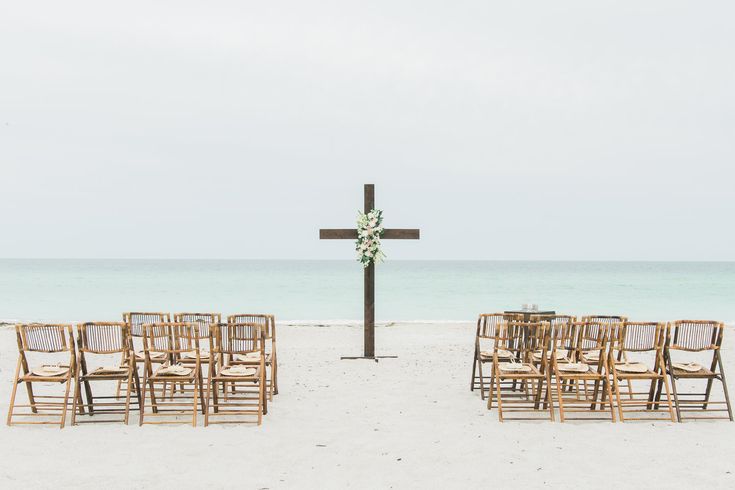 an empty beach with chairs and a cross in the sand