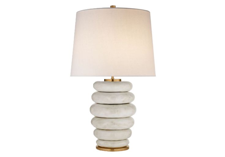 a white lamp with three stacked rocks on the bottom and a beige shade over it