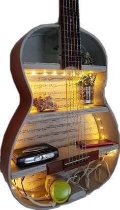 a guitar shaped shelf with musical instruments on it's sides and lights around the neck