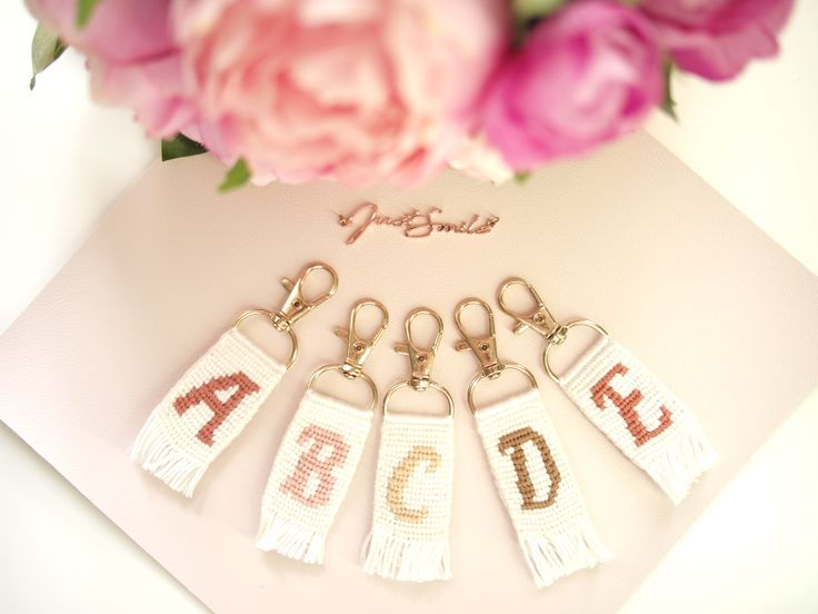 four key chains with letters and numbers on them sitting next to flowers in front of a card