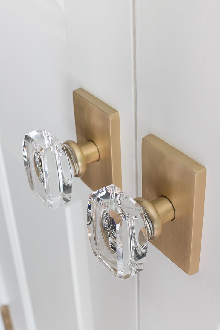 two glass door knobs on the front of a white door with gold hardware and handles