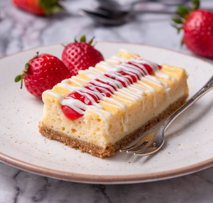 a piece of cheesecake on a plate with strawberries next to it and a fork