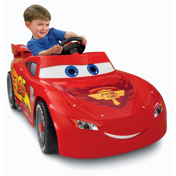 a young boy driving a red toy car