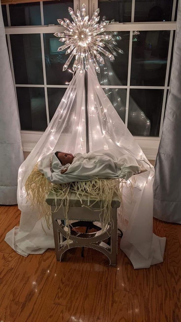 a nativity scene is displayed in front of a window with lights on the windowsill