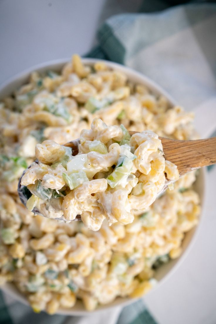 a white bowl filled with macaroni salad on top of a green and white checkered cloth