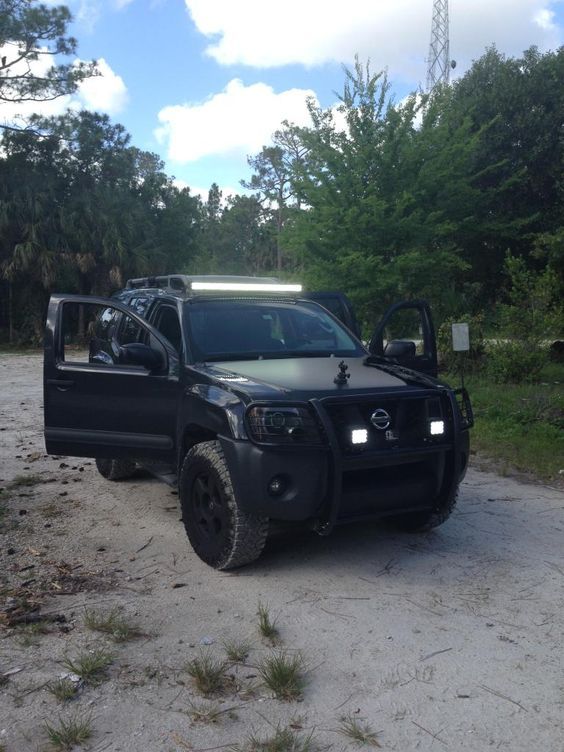 a black truck parked on top of a dirt road