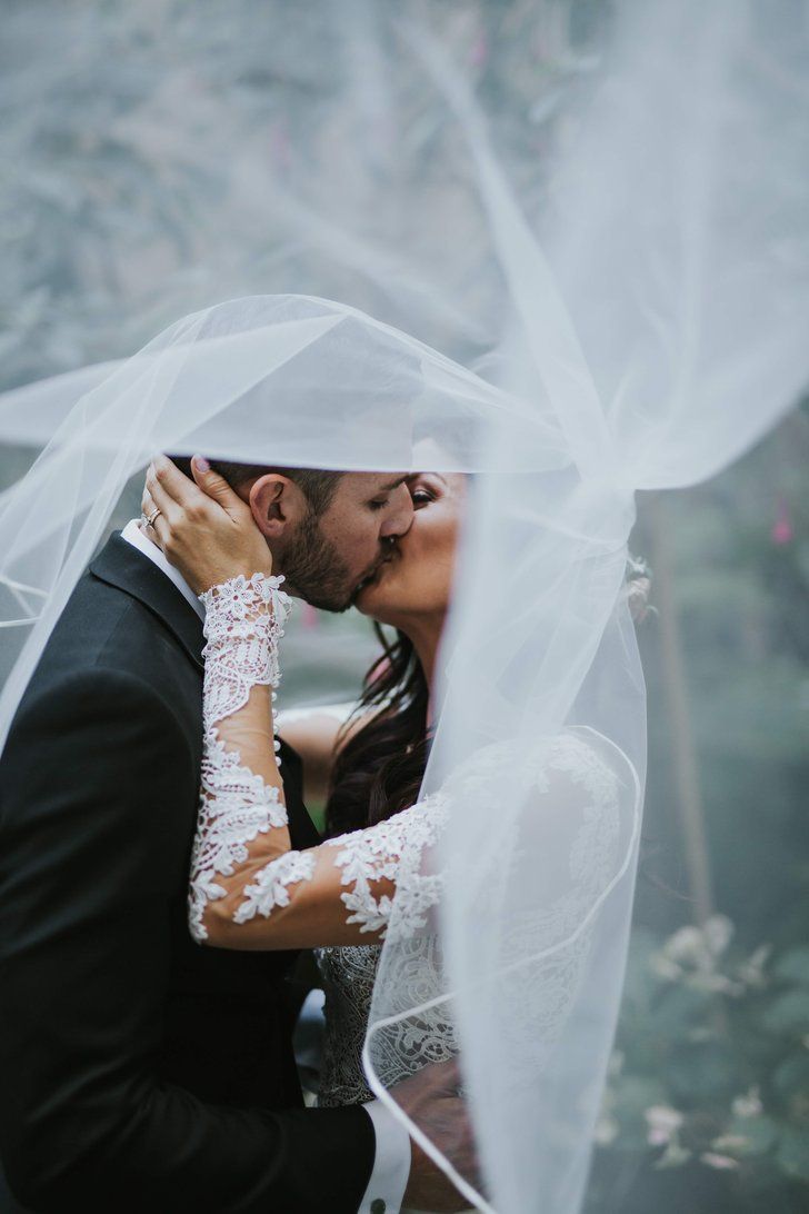 a bride and groom kissing under a veil