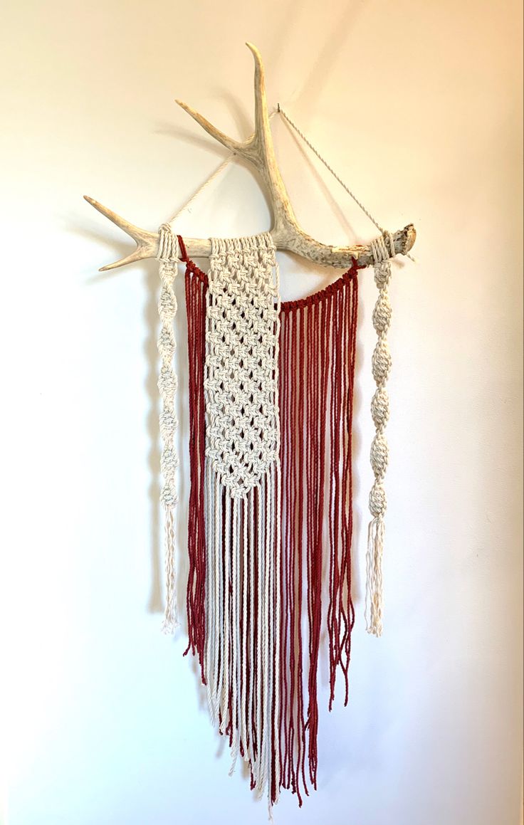 a deer antler hanging on the wall with macrame and crochet