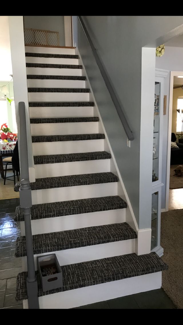 the stairs are painted black and white with gray carpeted treads that lead up to the second floor