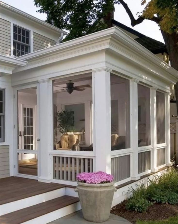 a large white house with a porch and flowers in the pot on the front steps